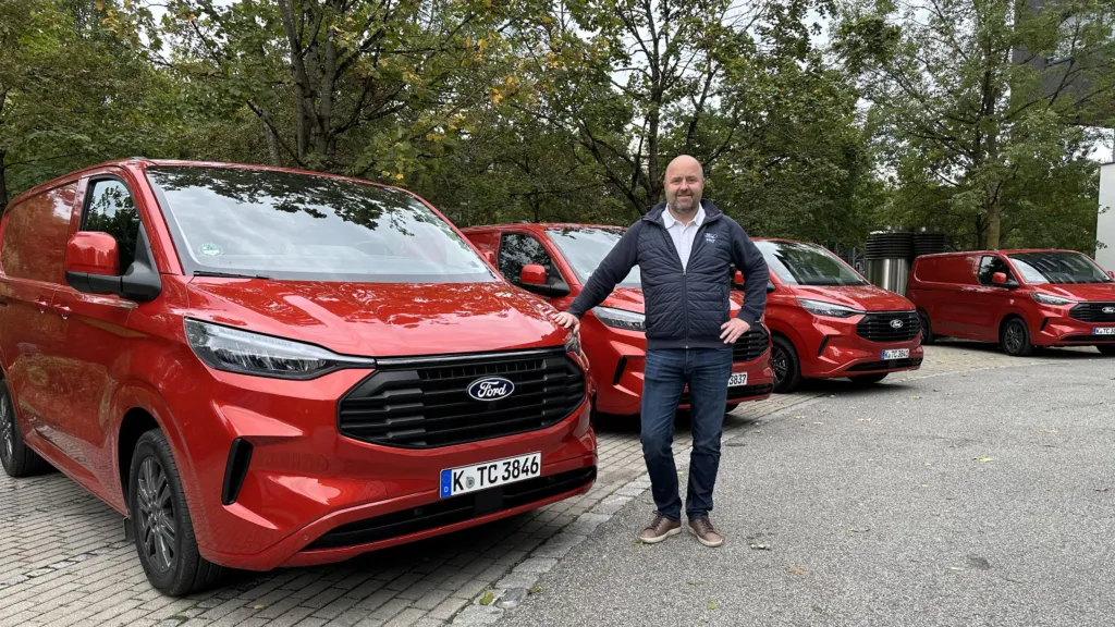 Mann står ved røde Ford varebiler.